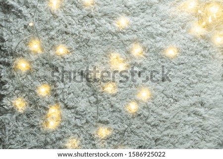 White fluffy wool background with glowing garlands top view