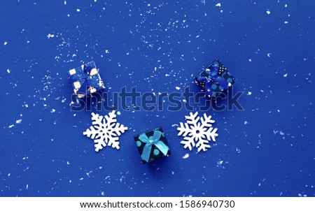 Gift boxes on a classic blue background with snow decor. Christmas or New Year holidays concept. Close-up, copy space