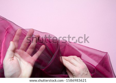 Top view of male hands holding a purple on a pink background, selective focus