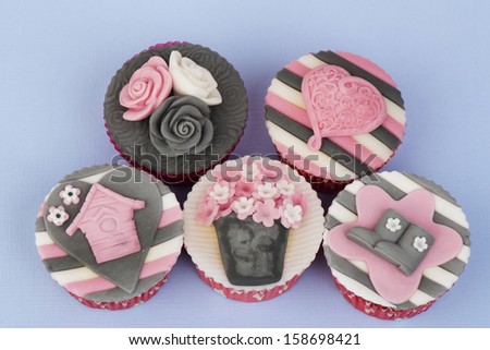 Spring decorated cupcakes in pink grey on a blue background
