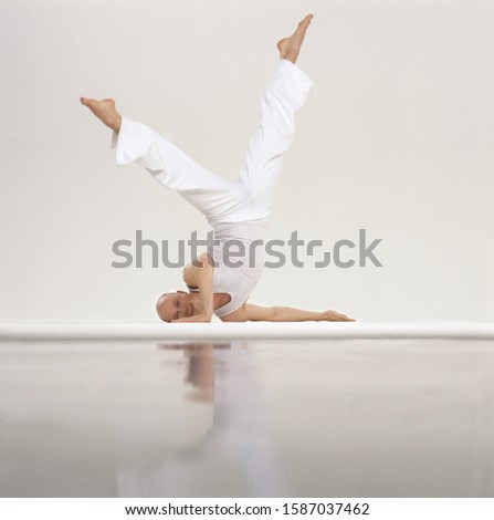 Male gymnast balances upside-down, with legs raised