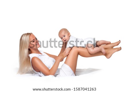 Beautiful happy blonde mom hugs baby. Sweet motherly love. girl holds child in her arms. Isolated on white background. Portrait of mother and small child on the bed