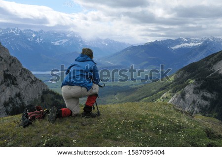 A single person kneeling on the ground while taking photos of the beautiful mountain views of the Canadian Rockies.