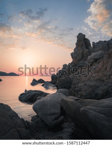 Colorful sunrise sky and clouds framed by rock formations on the coast of Sardinia, Italy