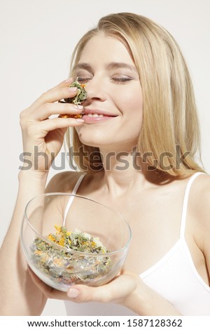 Young woman smelling dried herbs in studio
