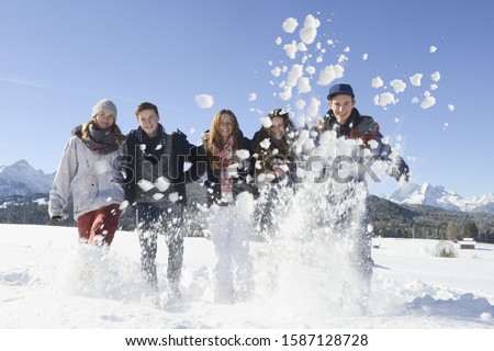 Portrait of young friends playing in snow at ski resort