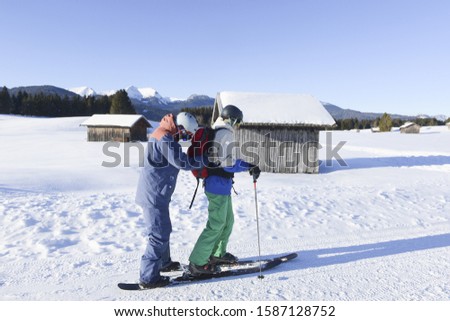 Young man teaching friend how to ski in mountain resort