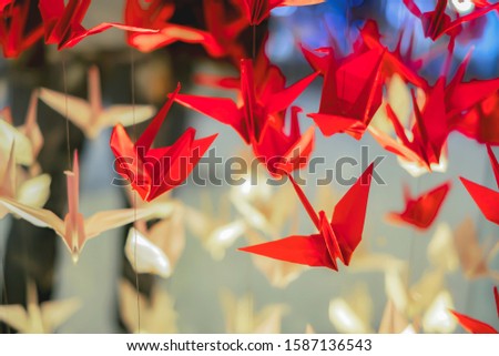 soft focus handicraft origami paper bird flock red and white color in the sky with blurred background they are a symbol of hope and healing during challenging times in Japanese called Senbazuru