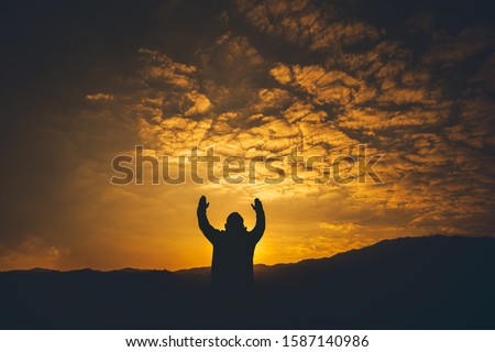 Man lift hands and Praying at sunset background. christian silhouette concept.