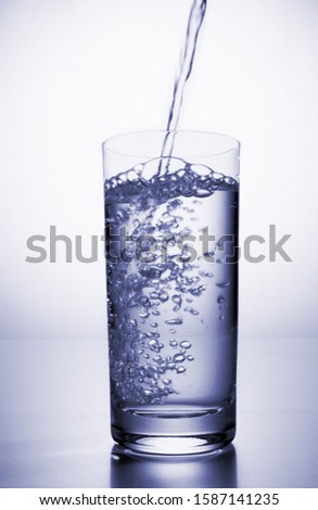 View of water being poured into a glass with a slice of lemon