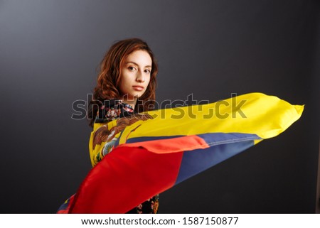 Ethnic Ecuadorian lady with the waving Ecuador flag isolated on gray background..