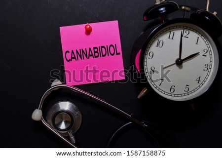 Cannabidiol write on sticky notes isolated on office desk. medical and education concept.