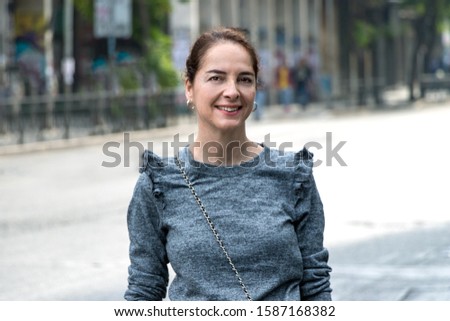 Portrait of a mature woman 45 - 50 years smiling looking camera over an urban - city background.