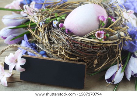 Easter Nest WIth A Purple Egg And A Blank Slate On A Wooden Background