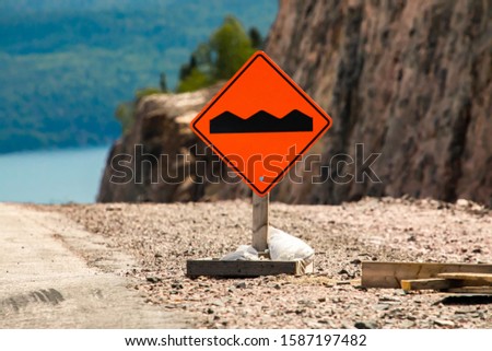 Bump or uneven pavement on the road ahead orange sign on the ground in selective focus view, Temporary condition road signs