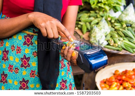 close up of an african woman selling in a local african market using a mobile point of sale device