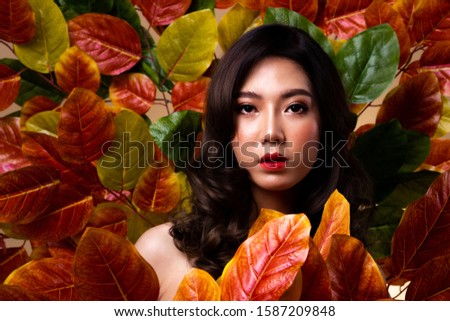 Queen of the Jungle, Asian Teenager woman with Fashion make up stand in middle of Red reddish leafs as forest, Studio lighting copy space, Green Tree save wood concept