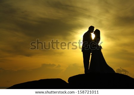 Silhouette of a couple before marriage Standing kissing on a rock Royalty-Free Stock Photo #158721011