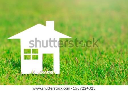 Beautiful white paper house on green grass field background