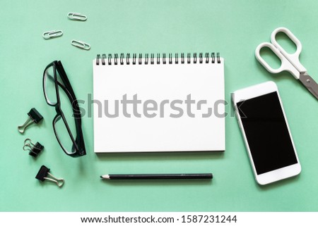 Creative workspace with open blank notebook with office accessories and mock up smartphone on colorful background