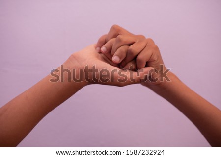Two hands knotted together against clear background