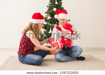 Happy couple with baby celebrating Christmas together at home.
