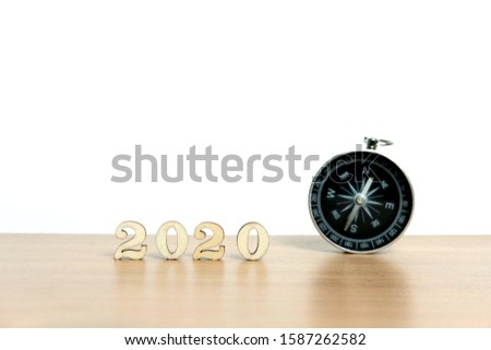 Miniature people - concept for happy new year 2020 with clock, compass and wooden number block
