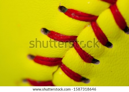 Yellow softball with red stitching close up 