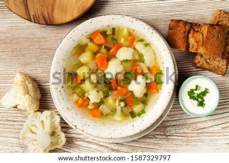 Vegetables soup with cauliflowers, onion, celery, carrots, tomatoes, potatoes, peas, zucchini.   Royalty-Free Stock Photo #1587329797