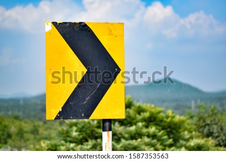 Broken Rusted Turn Right Road Sign Board on valley (Black and Yellow board with Arrow traffic Symbol)