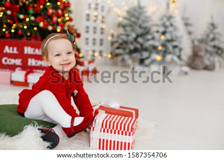 Little girl in Christmas decorated room. Christmas celebration. Girl weared in red dress. New year eve