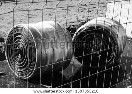 two construction metal coils lie on the ground behind a metal mesh
