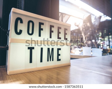 Coffee Time, text on the white light box, decoration on wooden table on cafe outdoor background with copy space.