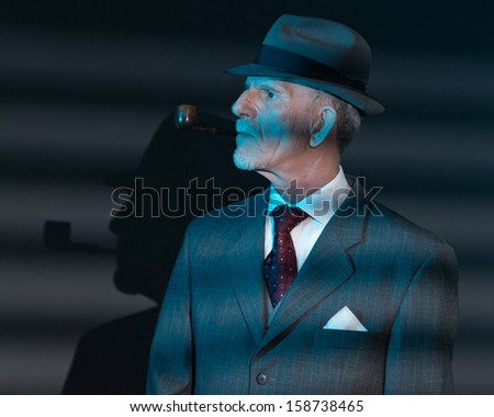 Retro detective man smoking pipe at night in office. Lit by light through venetian blinds.