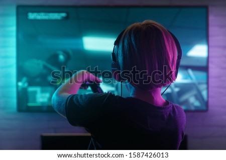 Little boy playing video game in the dark room Royalty-Free Stock Photo #1587426013