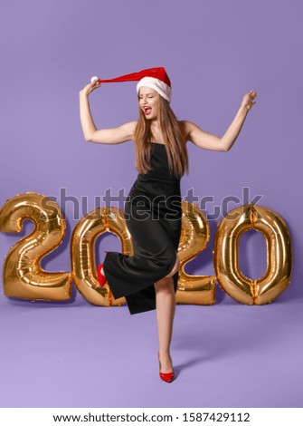Happy young woman in Santa Claus hat on color background