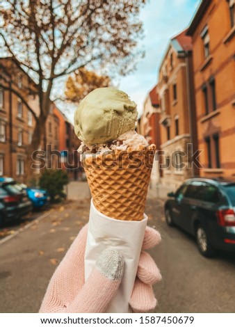 Autumn season in Germany. An ice cream being held in a hand with pink gloves. The image is facing a background of houses in Germany, Europe.