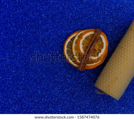 Natural beeswax candle on a blue background Organic handicraft object Romantic candle made for the holiday Dried orange slices, cinnamon. Background made in trendy classic blue color of the year 2020.