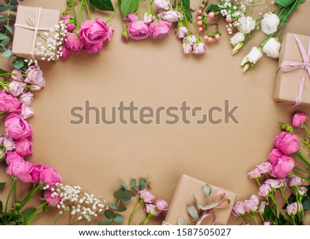 Valentines day concept. Frame of flowers and gift boxes on craft paper background with blank space for text. Top view, flat lay.