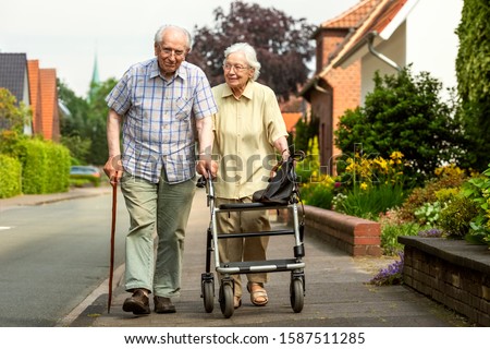 Elderly Couple with Walking Frame and Stick on the Sidewalk Royalty-Free Stock Photo #1587511285