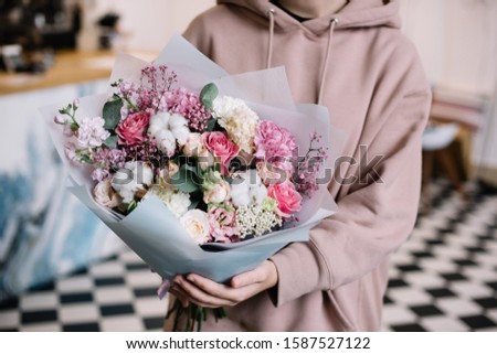 Very nice young woman holding big and beautiful bouquet of fresh carnations, cotton, roses, eustoma, matthiola flowers in pink and white colors, cropped photo, bouquet close up