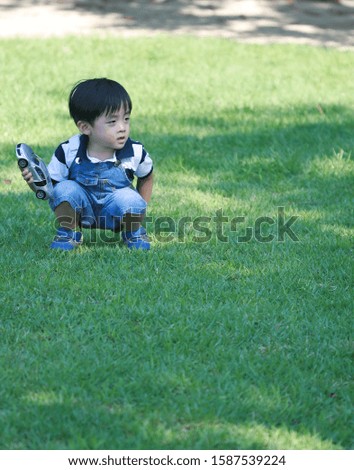 a picture of a son looking somewhere with a toy in the park.