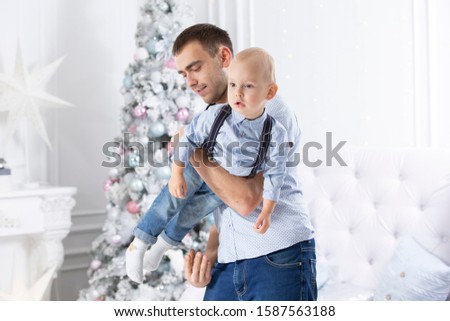 Father and child play against the background of a Christmas tree. Man and son in the new year.