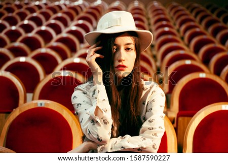 portrait of a pretty girl hipster in a movie theater posing in fashion style, dreaming alone