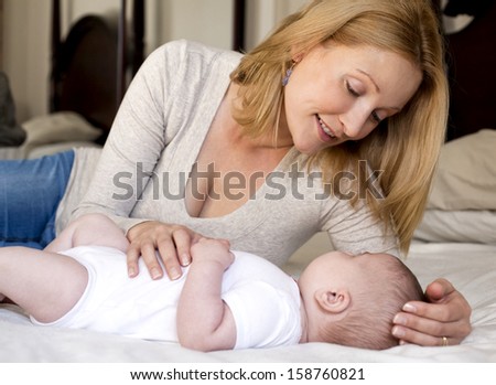 blond young mother with her baby lying in the bed