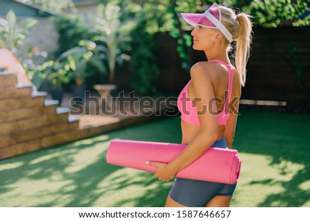 Young sporty woman holds yoga mat in her hands