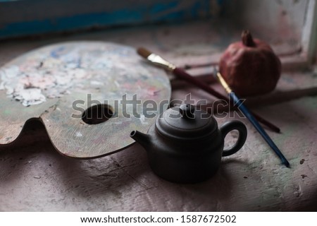 Palette for drawing by the artist. With paints of different colors. Lies on a wooden windowsill. Screensaver for your desktop. Kettle master. clay for Chinese tea ceremonies. Tassels and pomegranates.