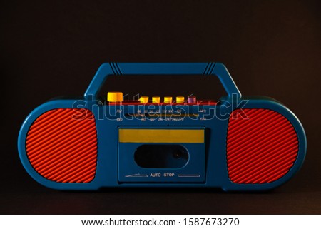 Old red-blue tape recorder on cassettes on a black background
