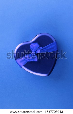 Blue heart-shaped box with ribbon on blue background
