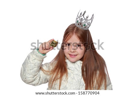 Studio image of a cute cheerful little girl in a warm white coat with a crown on his head holding a small gift isolated on white on Holiday